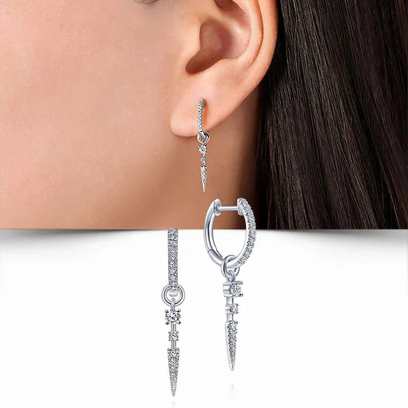 Close-up of blue cubic zirconia hoop earrings worn on the ear, showcasing elegant design and sparkle.