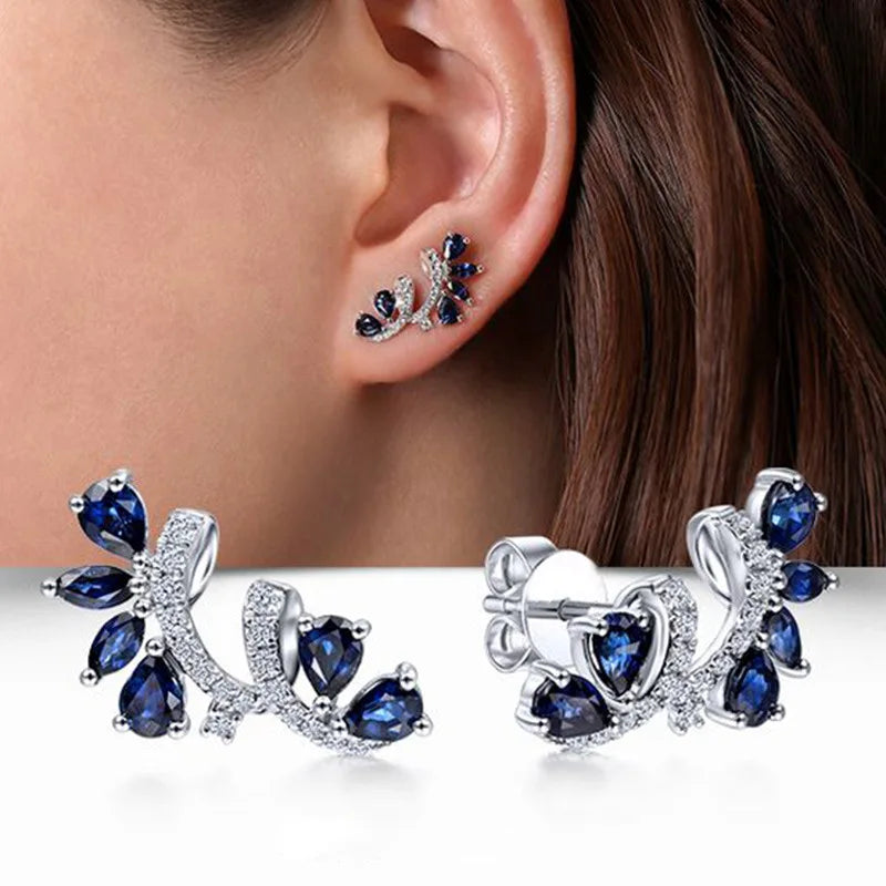 Blue cubic zirconia hoop earrings elegantly displayed on a woman's ear, showcasing their sparkling design.